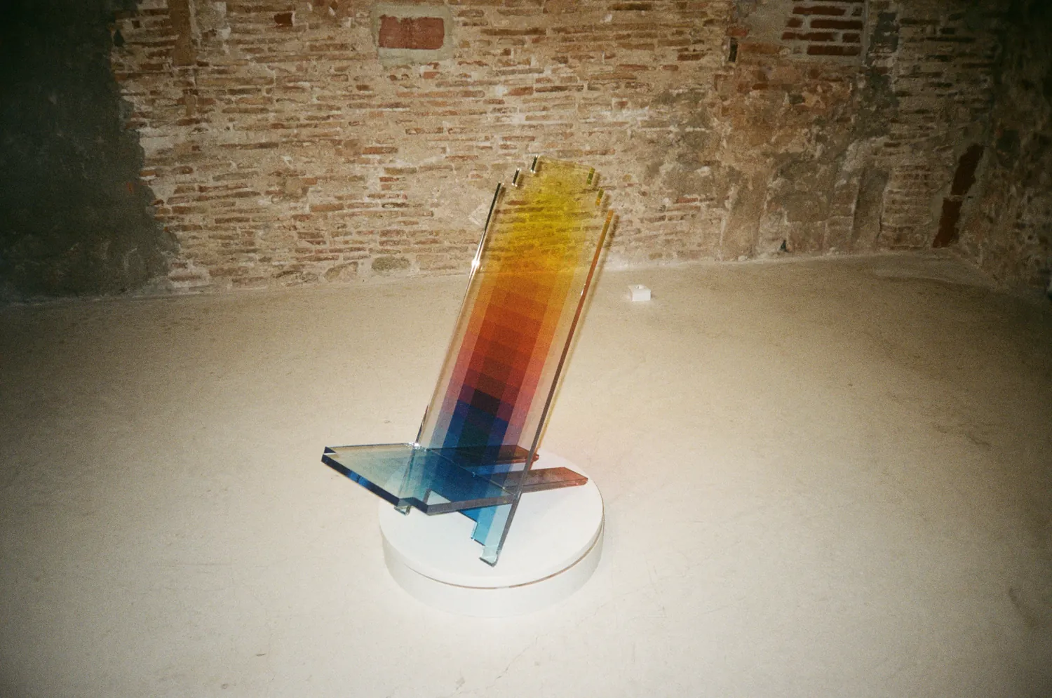 Pieza de Felipe Pantone sobre un pedestal, delante de una pared de ladrillo